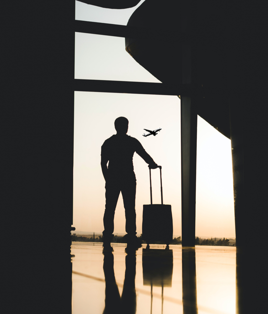 Silhouette of a man stood at an airport with a suitcase.